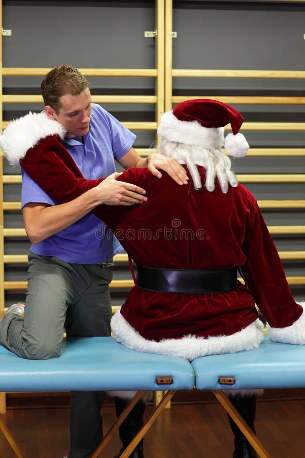 Terapista maschio che massaggia Santa Claus sollecitata fotografie stock Terapista maschio che massaggia Santa Claus sollecitata fotografie stock