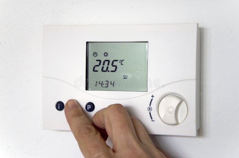 Hand adjusting the thermostat of a heating system. Hand adjusting the thermostat of a heating system