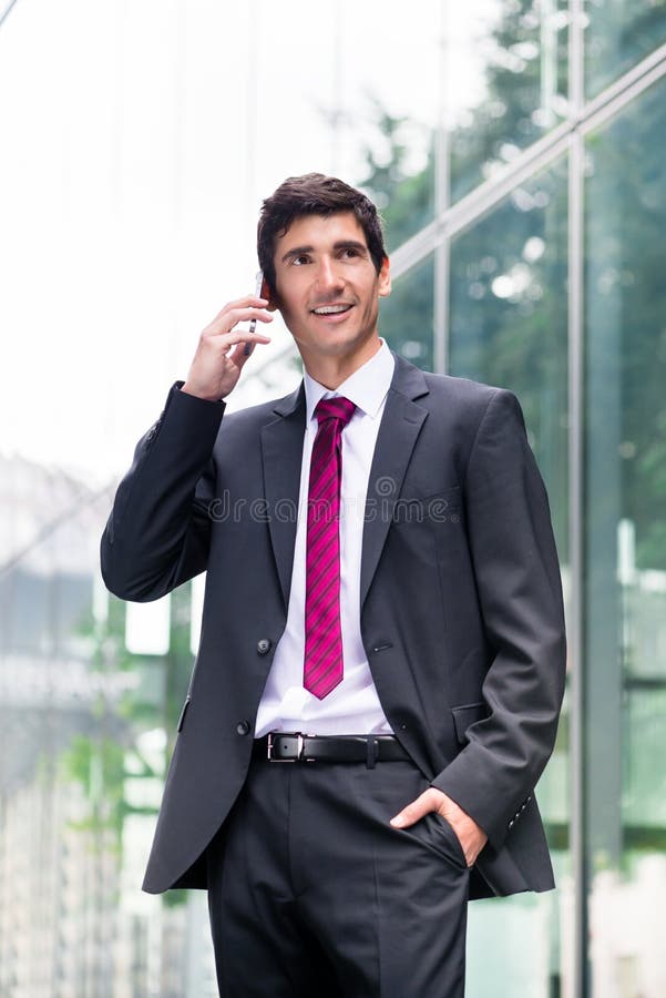 Terno de negócio vestindo feliz do homem novo ao falar no pH móvel fotos de stock Terno de negócio vestindo feliz do homem novo ao falar no pH móvel fotos de stock