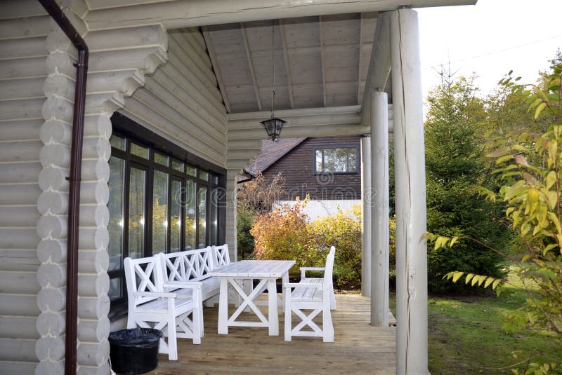 Terrasse en bois de vieille maison de campagne avec les meubles en bois blancs photographie stock libre de droits Terrasse en bois de vieille maison de campagne avec les meubles en bois blancs photographie stock libre de droits