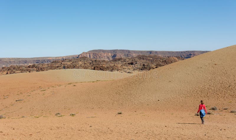 Terreno incolto d'escursione femminile sportivo del deserto attraverso il cratere vulcanico fotografie stock libere da diritti Terreno incolto d'escursione femminile sportivo del deserto attraverso il cratere vulcanico fotografie stock libere da diritti
