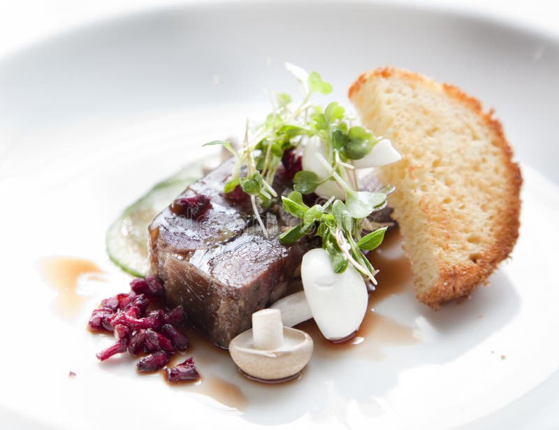 Pomegranate glaze, micro herbs, pickled cucumber and toasted brioche on a white plate as a starter dish. Pomegranate glaze, micro herbs, pickled cucumber and toasted brioche on a white plate as a starter dish.