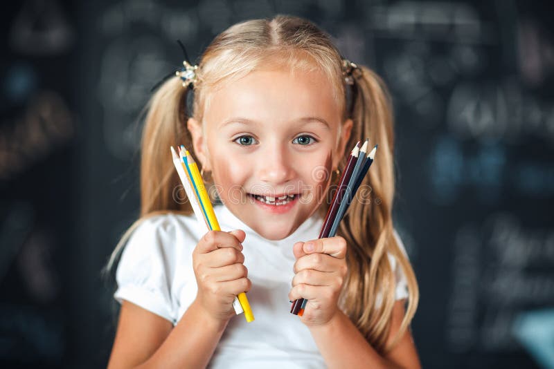 Terug naar school! Het portret glimlacht een weinig meisjestribunes met de kleurpotloden van de meisjesholding dichtbij het gezic royalty-vrije stock afbeeldingen Terug naar school! Het portret glimlacht een weinig meisjestribunes met de kleurpotloden van de meisjesholding dichtbij het gezic royalty-vrije stock afbeeldingen