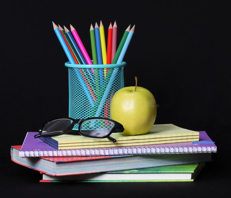 Terug naar schoolconcept. Een appel, kleurpotloden en glazen op stapel van boeken over zwarte royalty-vrije stock foto Terug naar schoolconcept. Een appel, kleurpotloden en glazen op stapel van boeken over zwarte royalty-vrije stock foto
