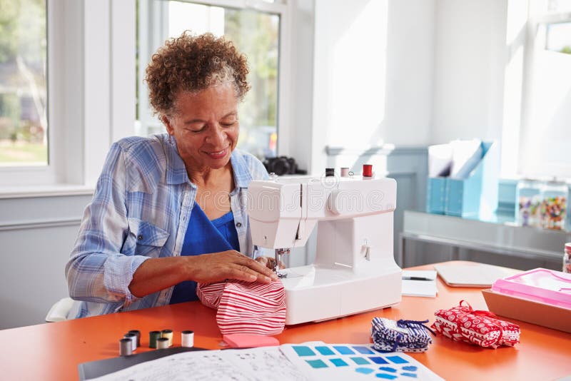 Tessuto di cucitura della donna di colore senior facendo uso di una macchina per cucire