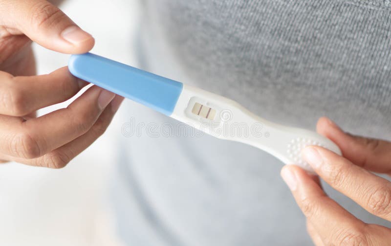 Test di gravidanza della tenuta della mano della donna del primo piano con il momento felice, concetto di sanità, fuoco selettivo immagini stock Test di gravidanza della tenuta della mano della donna del primo piano con il momento felice, concetto di sanità, fuoco selettivo immagini stock