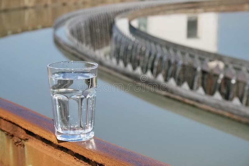 Vetro, riempito con acqua dopo in piedi vicino all'impianto di trattamento.