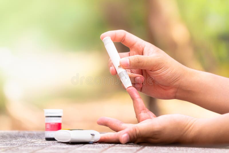Tester di glucosio di anima Chiuda su delle mani della donna facendo uso della lancetta sul dito per controllare il livello della fotografia stock Tester di glucosio di anima Chiuda su delle mani della donna facendo uso della lancetta sul dito per controllare il livello della fotografia stock