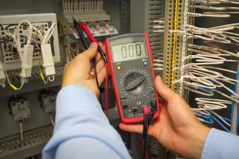 Tester in hand of electric engineer in automation panel. Adjust electric panel with multimeter royalty free stock photo