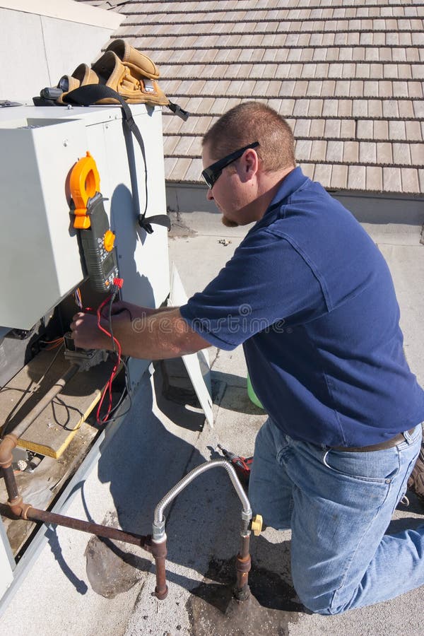 Repair man testing air conditioner unit with voltage metering equipment on roof. Repair man testing air conditioner unit with voltage metering equipment on roof