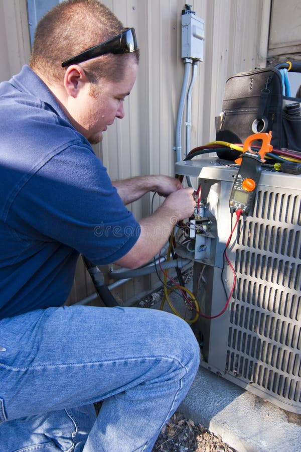 Repair man testing air conditioner unit with voltage metering equipment. Repair man testing air conditioner unit with voltage metering equipment