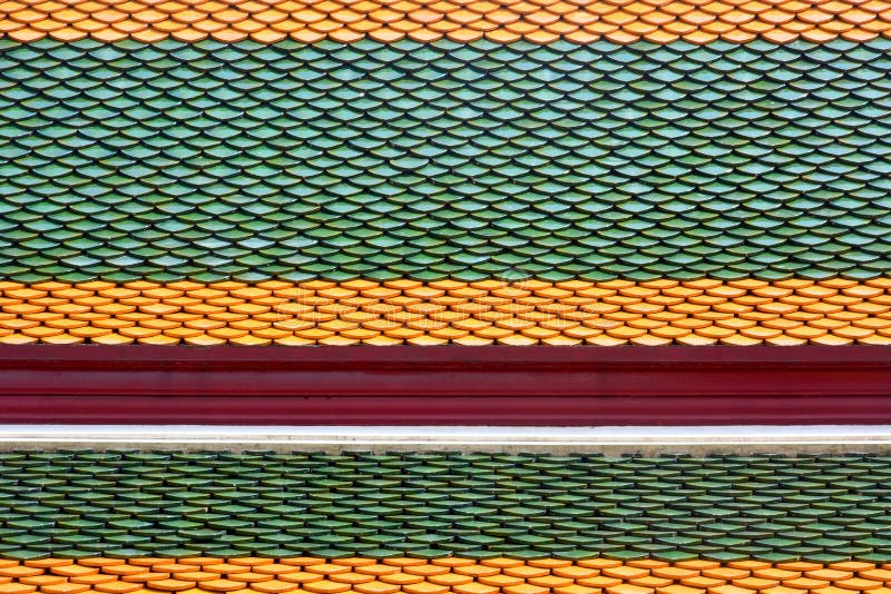 Tetto thailandese di antico stile in un tempio buddista, strato di tegole colorate di argilla in fondo al tetto immagine stock libera da diritti Tetto thailandese di antico stile in un tempio buddista, strato di tegole colorate di argilla in fondo al tetto immagine stock libera da diritti