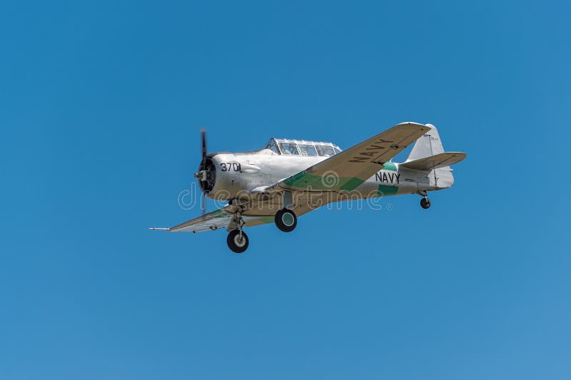 EDEN PRAIRIE, MN - JULY 16, 2016: AT-6 Texan airplane comes in for a landing against clear blue sky at air show. The AT-6 Texan was primarily used as trainer aircraft during and after World War II. EDEN PRAIRIE, MN - JULY 16, 2016: AT-6 Texan airplane comes in for a landing against clear blue sky at air show. The AT-6 Texan was primarily used as trainer aircraft during and after World War II.