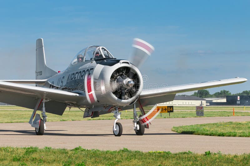 EDEN PRAIRIE, MN - JULY 16 2016: AT-6 Texan airplane powers down engine after landing landing at air show. The AT-6 Texan was primarily used as trainer aircraft during and after World War II. EDEN PRAIRIE, MN - JULY 16 2016: AT-6 Texan airplane powers down engine after landing landing at air show. The AT-6 Texan was primarily used as trainer aircraft during and after World War II.