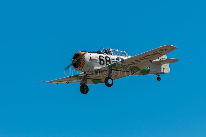 EDEN PRAIRIE, MN - JULY 16, 2016: AT-6 Texan airplane with purple and yellow nose flies by at air show. The AT-6 Texan was primarily used as trainer aircraft during and after World War II. EDEN PRAIRIE, MN - JULY 16, 2016: AT-6 Texan airplane with purple and yellow nose flies by at air show. The AT-6 Texan was primarily used as trainer aircraft during and after World War II.