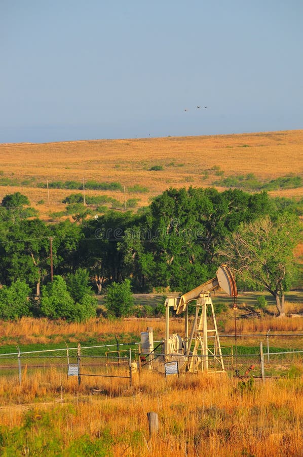 Texas Oil Well met Blauwe Hemel en Gouden Golven van Inheemse Grassess stock foto Texas Oil Well met Blauwe Hemel en Gouden Golven van Inheemse Grassess stock foto