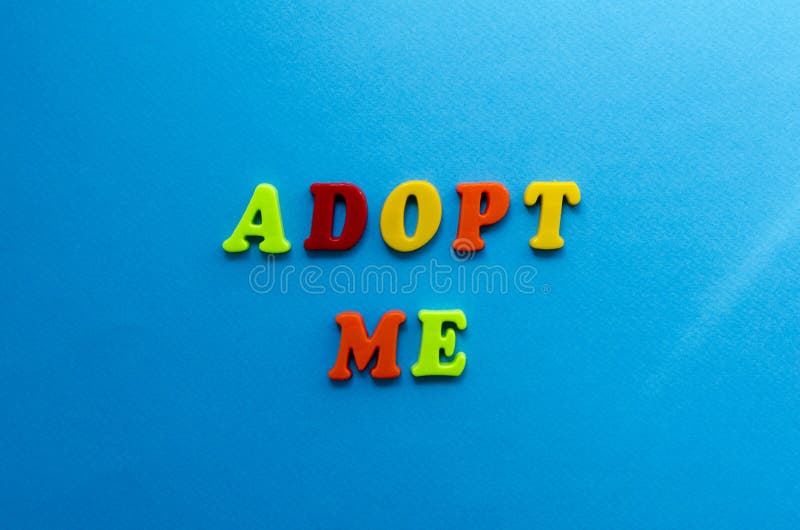 Text adopt me from plastic colored letters on blue paper background royalty free stock photos