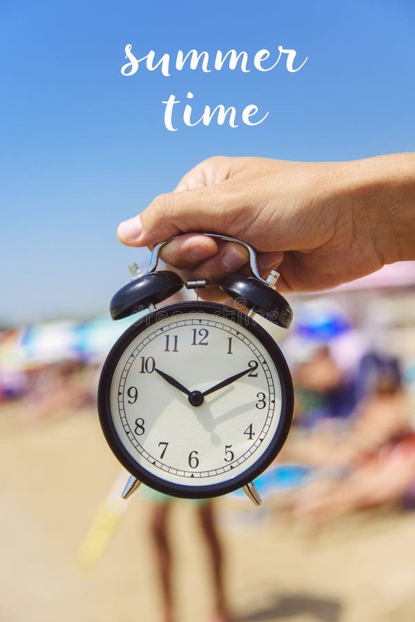 Text horas de verão e um despertador na praia imagem de stock