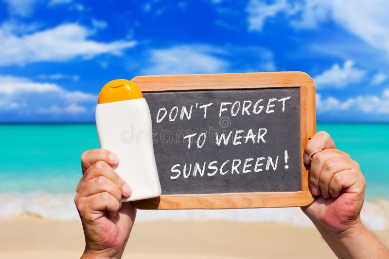 Human Hands hold a bottle sunscreen and a slate blackboard with text message Don�t forget to wear Sunscreen. Human Hands hold a bottle sunscreen and a slate blackboard with text message Don�t forget to wear Sunscreen