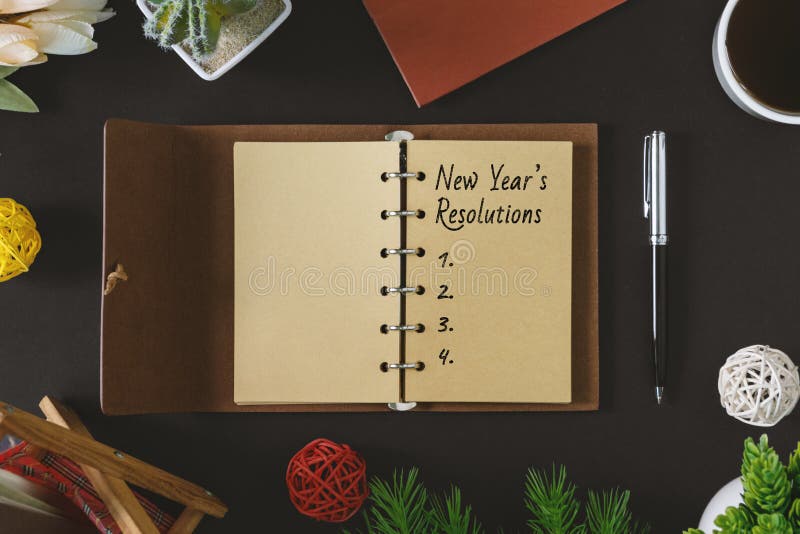 Texto das definições do ano novo no bloco de notas rústico com pena e no café no fundo preto imagens de stock royalty free Texto das definições do ano novo no bloco de notas rústico com pena e no café no fundo preto imagens de stock royalty free