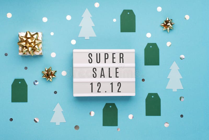 12.12 Super Sale text on white lightbox, with gold gift box and Christmas decorations on blue paper background. Double 12 Mega sales day concept. Top view, flat lay, copy space. 12.12 Super Sale text on white lightbox, with gold gift box and Christmas decorations on blue paper background. Double 12 Mega sales day concept. Top view, flat lay, copy space