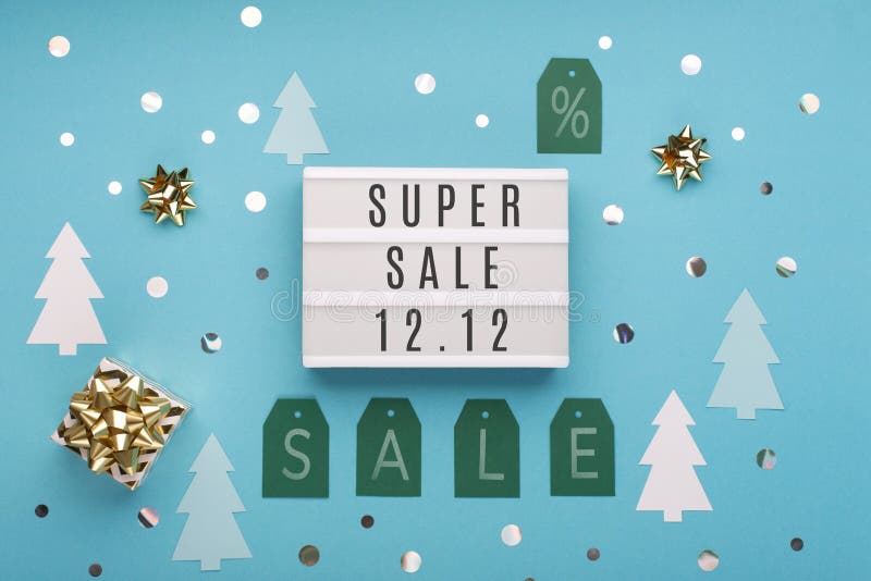 12.12 Super Sale text on white lightbox, with gold gift box and Christmas decorations on blue paper background. Double 12 Mega sales day concept. Top view, flat lay, copy space. 12.12 Super Sale text on white lightbox, with gold gift box and Christmas decorations on blue paper background. Double 12 Mega sales day concept. Top view, flat lay, copy space