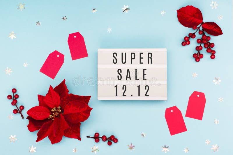 12.12 Super Sale text on white lightbox, Christmas flower poinsettia, red paper tags and snowflakes on blue background. Singles day concept. Online shopping of China. Top view, copy space. 12.12 Super Sale text on white lightbox, Christmas flower poinsettia, red paper tags and snowflakes on blue background. Singles day concept. Online shopping of China. Top view, copy space