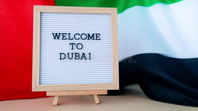 Texto del marco bienvenido a dubai sobre el fondo de ondear la bandera de uae hecha de seda. bandera de los emiratos árabes unidos