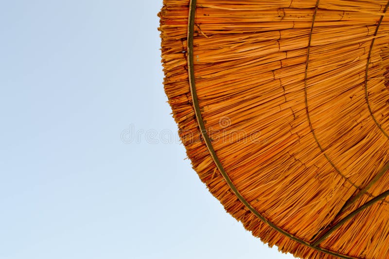 Textura dos guarda-sóis naturais da palha bonita feitos do feno em um recurso tropical do deserto, descansando contra foto de stock Textura dos guarda-sóis naturais da palha bonita feitos do feno em um recurso tropical do deserto, descansando contra foto de stock