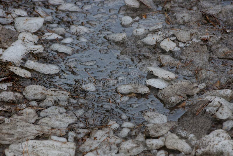 Textura natural de pedazos de hielo gris y de agua fangosa en un charco fotografía de archivo Textura natural de pedazos de hielo gris y de agua fangosa en un charco fotografía de archivo