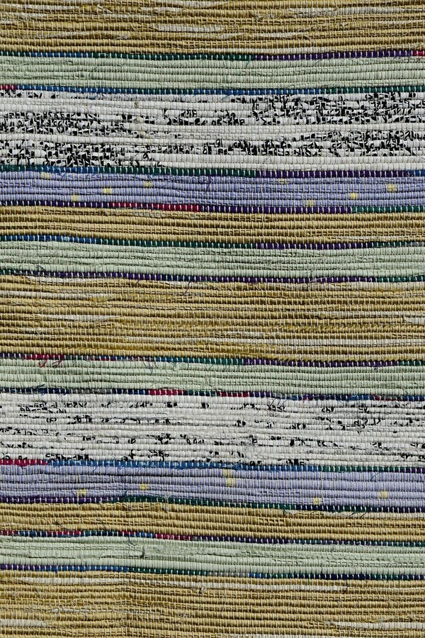 Texture of handmade carpet made on hand-loom, pattern of yellow, green, blue, white and black pastel vertical lines divided by thi