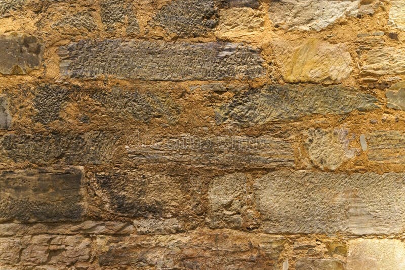 The texture of the old medieval wall of the house, lined with brown stone stock image