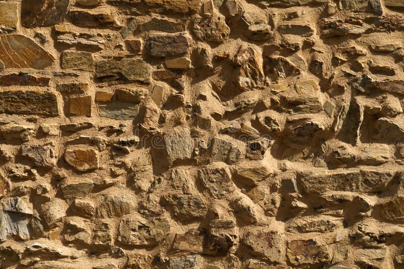 The texture of the old medieval wall of the house, lined with brown stone royalty free stock image
