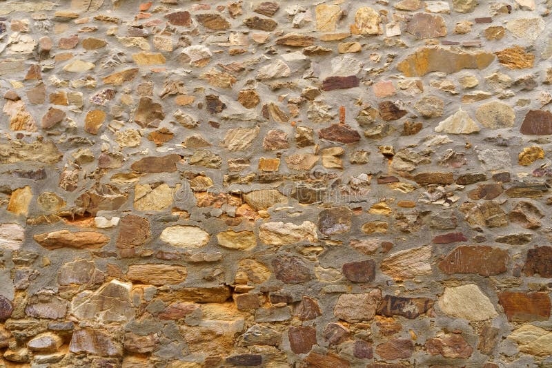 The texture of the old medieval wall of the house, lined with brown stone stock image