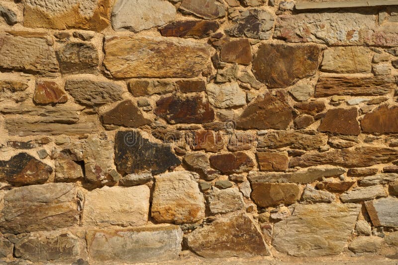 The texture of the old medieval wall of the house, lined with brown stone stock photography