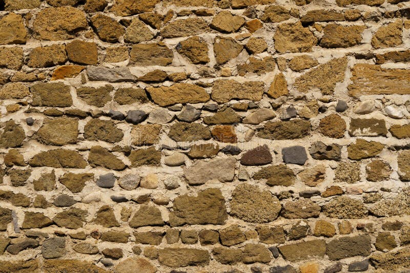 The texture of the old medieval wall of the house, lined with brown stone stock image