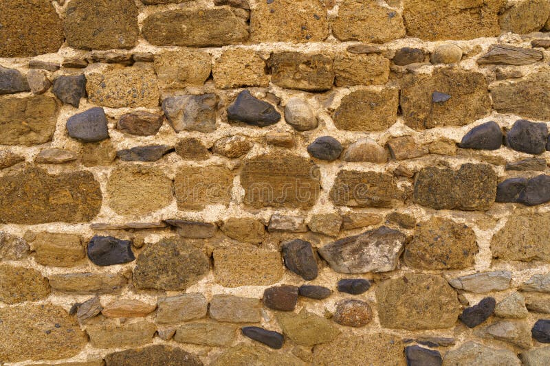 The texture of the old medieval wall of the house, lined with brown stone stock photography