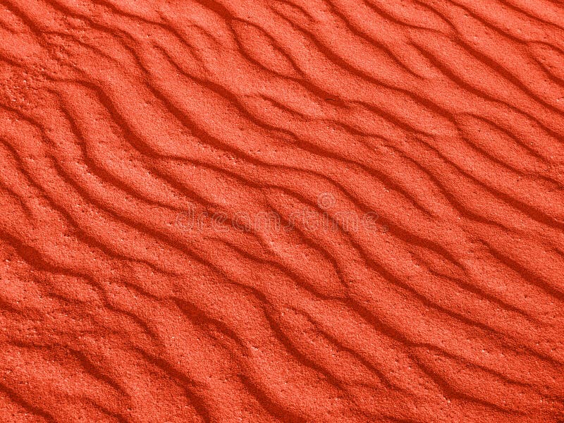 Texture of red sand waves on the beach or in the desert. the ripples of the sand is diagonal.