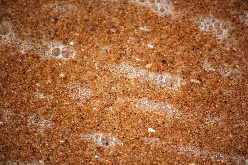 Texture of wet sand and ocean bubbles