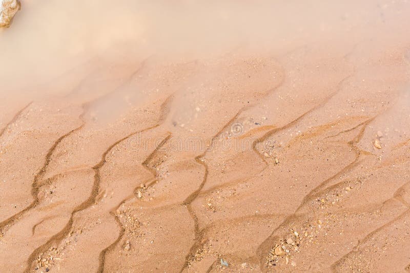Texture of wet sand and water closeup.