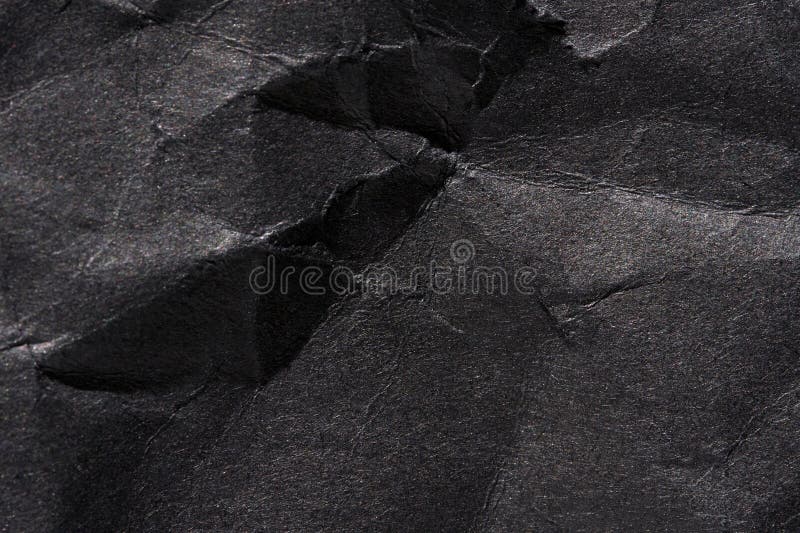 Textured black wrinkled paper surface with creases and shadows for abstract or background design royalty free stock image