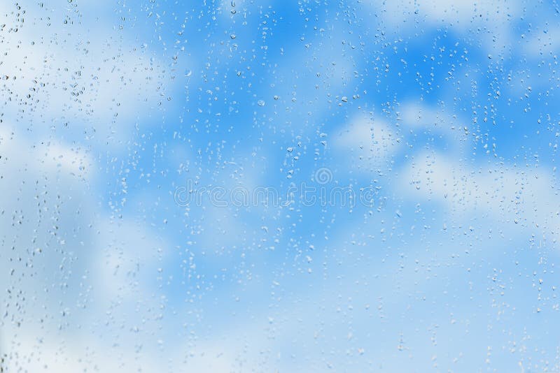 Textured blue background of sky, natural water drops on window glass, rain texture. Concept of clear, pure, bright