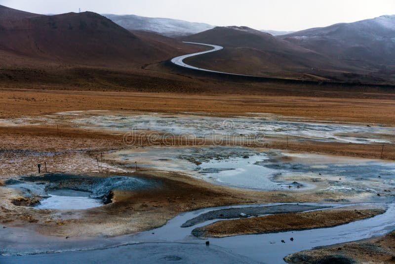 Textured, cracked and patterned ground in the Namaskard/Myvatn area in Icelandic nature. S shaped road and snow covered mountains in the background. Minerals royalty free stock photography Textured, cracked and patterned ground in the Namaskard/Myvatn area in Icelandic nature. S shaped road and snow covered mountains in the background. Minerals royalty free stock photography