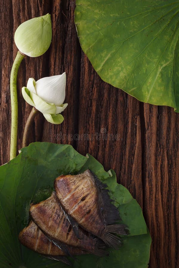 Thai food dried salted damsel fish fried with flower lotus jasmine decoration on wooden background beautiful flat lay still life r