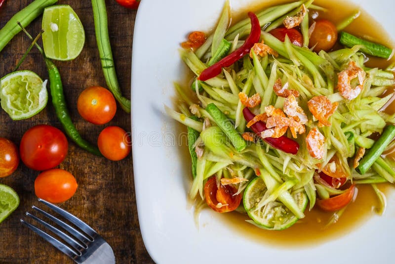 Thai food, papaya salad and tomatoes, peppers and condiments on a wooden table stock photos Thai food, papaya salad and tomatoes, peppers and condiments on a wooden table stock photos