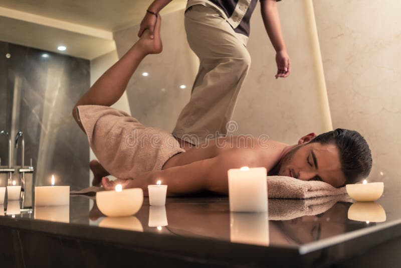 Thai massage practitioner massaging man through stretching techniques