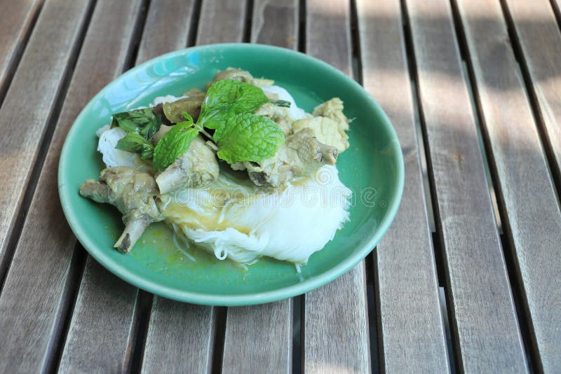 Thai Noodles with Chicken Curry (Kanom jeen) in a green dish.