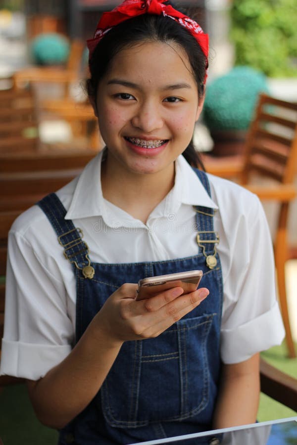 Thai student teen beautiful girl using her smart phone and smile.