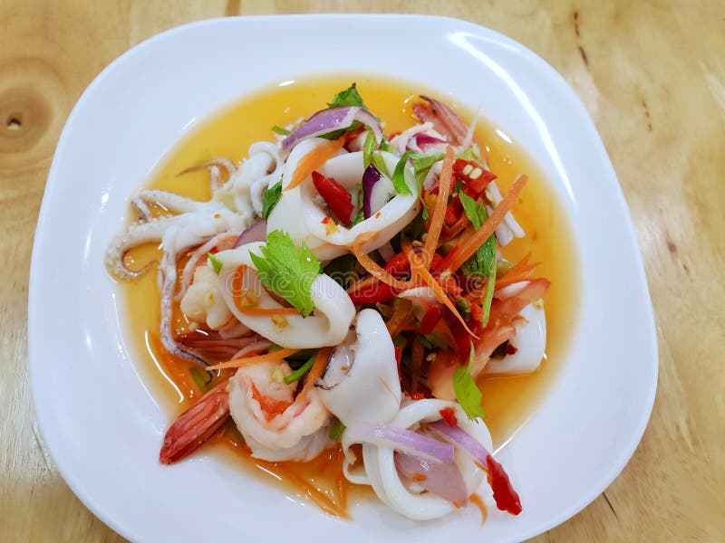 Thailändsk matstil, bästa sikt av kryddig thailändsk havs- sallad på den vita plattan på trätabellen arkivfoto Thailändsk matstil, bästa sikt av kryddig thailändsk havs- sallad på den vita plattan på trätabellen arkivfoto