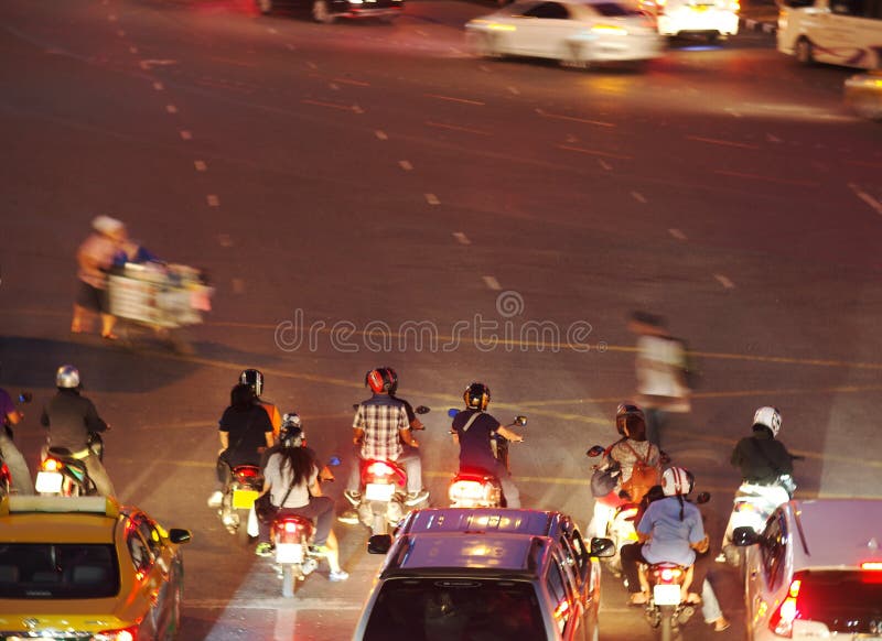 Thailändskt folk som rider små motorcyklar som väntar på rött fylligt arkivbild Thailändskt folk som rider små motorcyklar som väntar på rött fylligt arkivbild